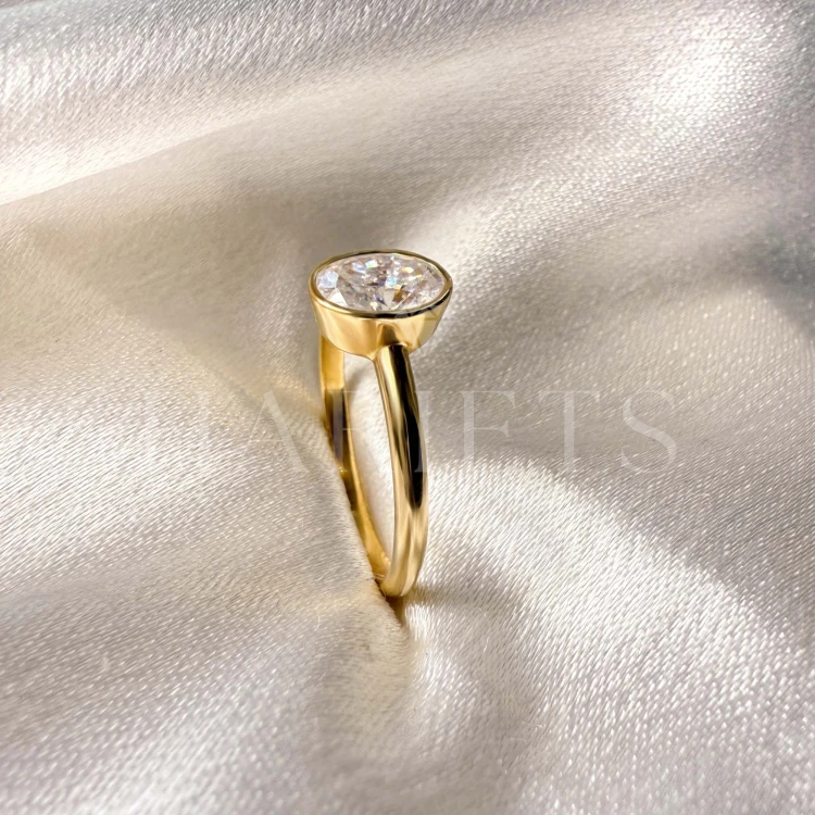 bague-de-fiancailles-bezel-moissanite-0-5ct-taille-ovale-gros-plan-profil-or-jaune-pure-hariets.jpg