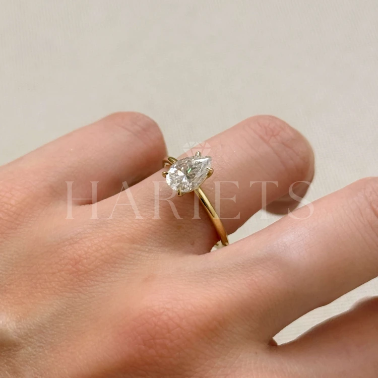 bague-de-fiançailles-solitaire-lumiere-moissanite-1-5ct-poire-or-jaune-gros-plan-au-doigt-hariets.jpg