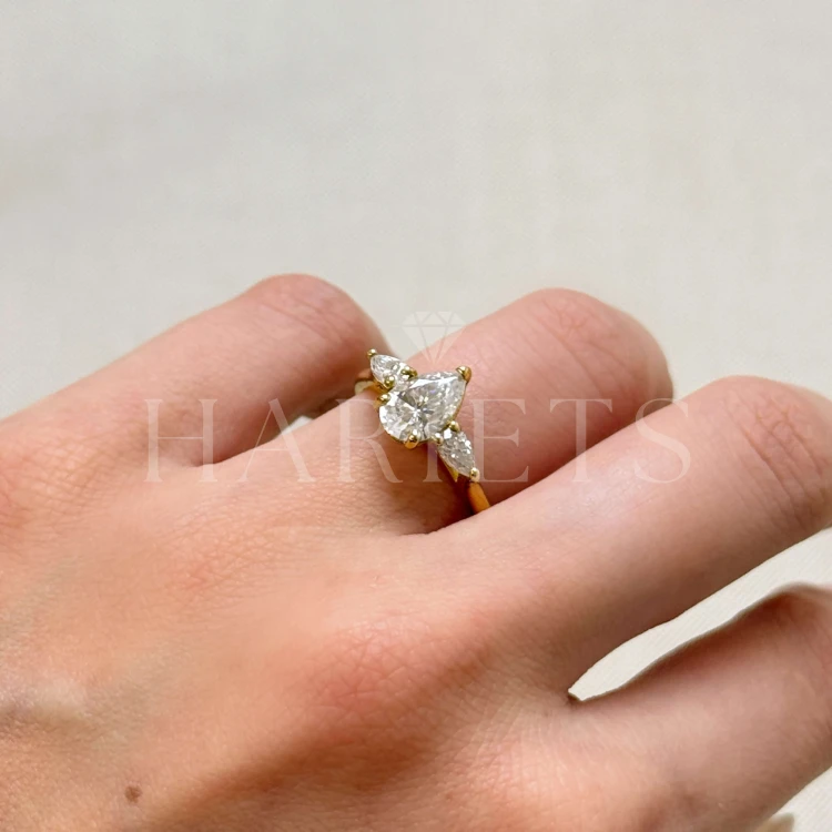bague-fiancailles-trinity-amara-moissanite-1-5ct-taille-poire-centrale-cote-sur-doigt-or-jaune-hariets.jpg