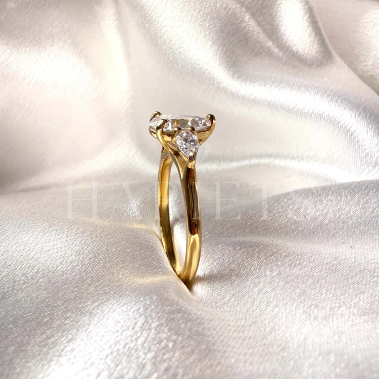 bague-fiancailles-trinity-amara-moissanite-1-5ct-taille-poire-centrale-gros-plan-cote-or-jaune-hariets.jpg