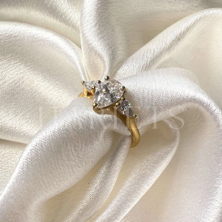 bague-fiancailles-trinity-amara-moissanite-1-5ct-taille-poire-centrale-gros-plan-or-jaune-hariets.jpg