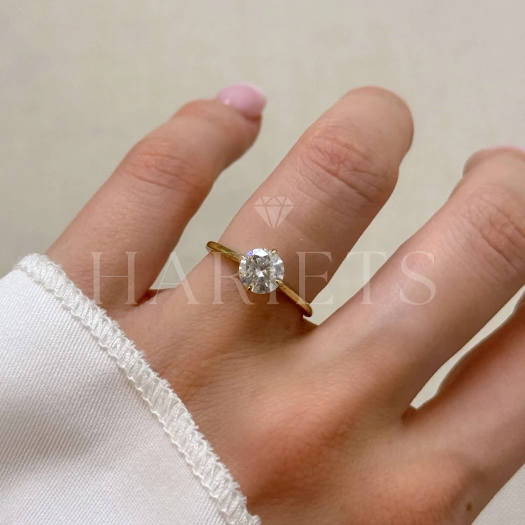 bague-fiancailles-solitaire-aura-moissanite-1ct-taille-brillant-sur-main-or-jaune-hariets.jpg