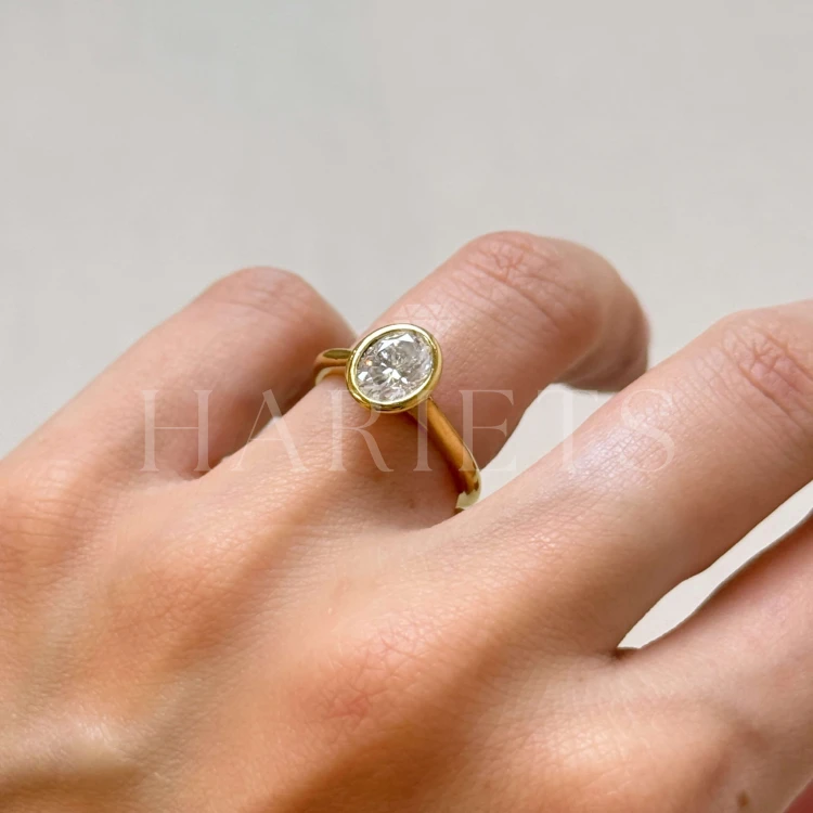 bague-fiancailles-bezel-moissanite-1-2ct-taille-ovale-sur-doigt-gros-plan-or-jaune-amora-hariets.jpg