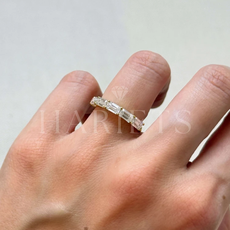 bague-avec-cinq-moissanites-2ct-taille-éméraude-sur-le-doigt-gros-plan-or-jaune-esmera-hariets