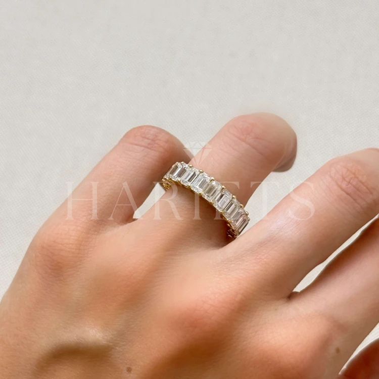 bague-eternity-avec-moissanites-taille-emeraude-sur-le-doigt-gros-plan-or-jaune-hariets