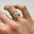 bague-de-fiancailles-solitaire-moissanite-2ct-taille-ovale-hidden-halo-or-jaune-portee-au-doigt-gros-plan-noelle-hariets.jpg